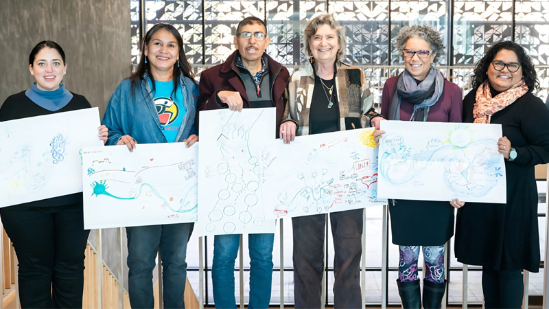 a group of people smiling holding artwork